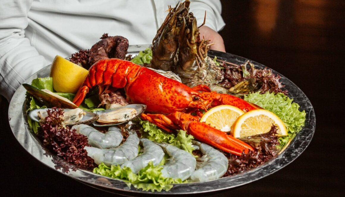 waiter holding seafood platter with lobster king prawns and mussels